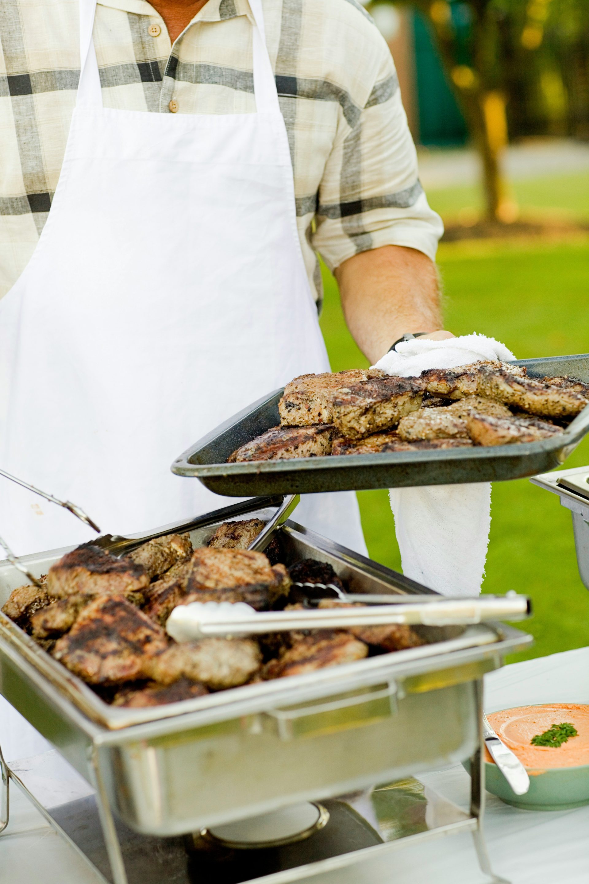 Person, die ein Tablett mit gegrilltem Fleisch hält